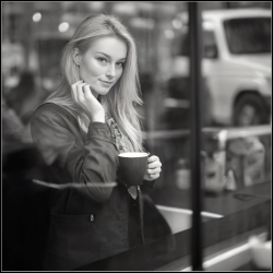 Kvinde men et forfrende smil, kigger ud af vinduet fra en lokal coffee shop