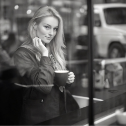 Kvinde men et forfrende smil, kigger ud af vinduet fra en lokal coffee shop